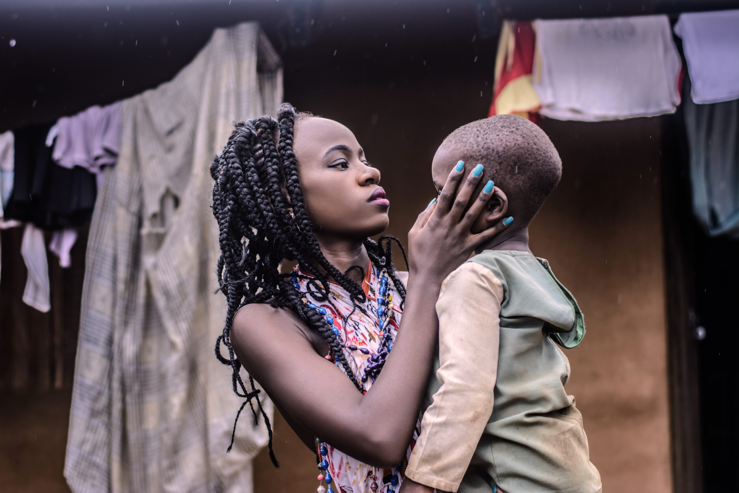 Girl with braided hair standing while carrying boy wearing beige long sleeved top